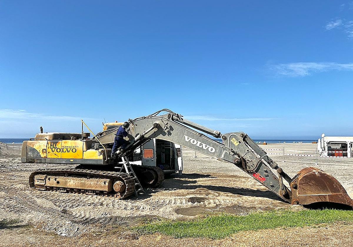 Un soldador arregla el brazo de la excavadora en Playa Granada.