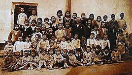 Los antiguos alumnos con su maestro y maestra en la puerta de la escuela de Melicena