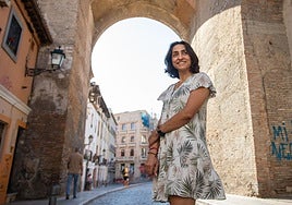 Walaa Zaiter, profesional del sector humanitario refugiada en Granada, posa sonriente bajo la Puerta de Elvira.