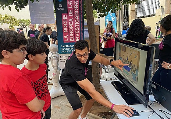 Dos escolares escuchan con atención y sorpresa la explicación de uno de los voluntarios.