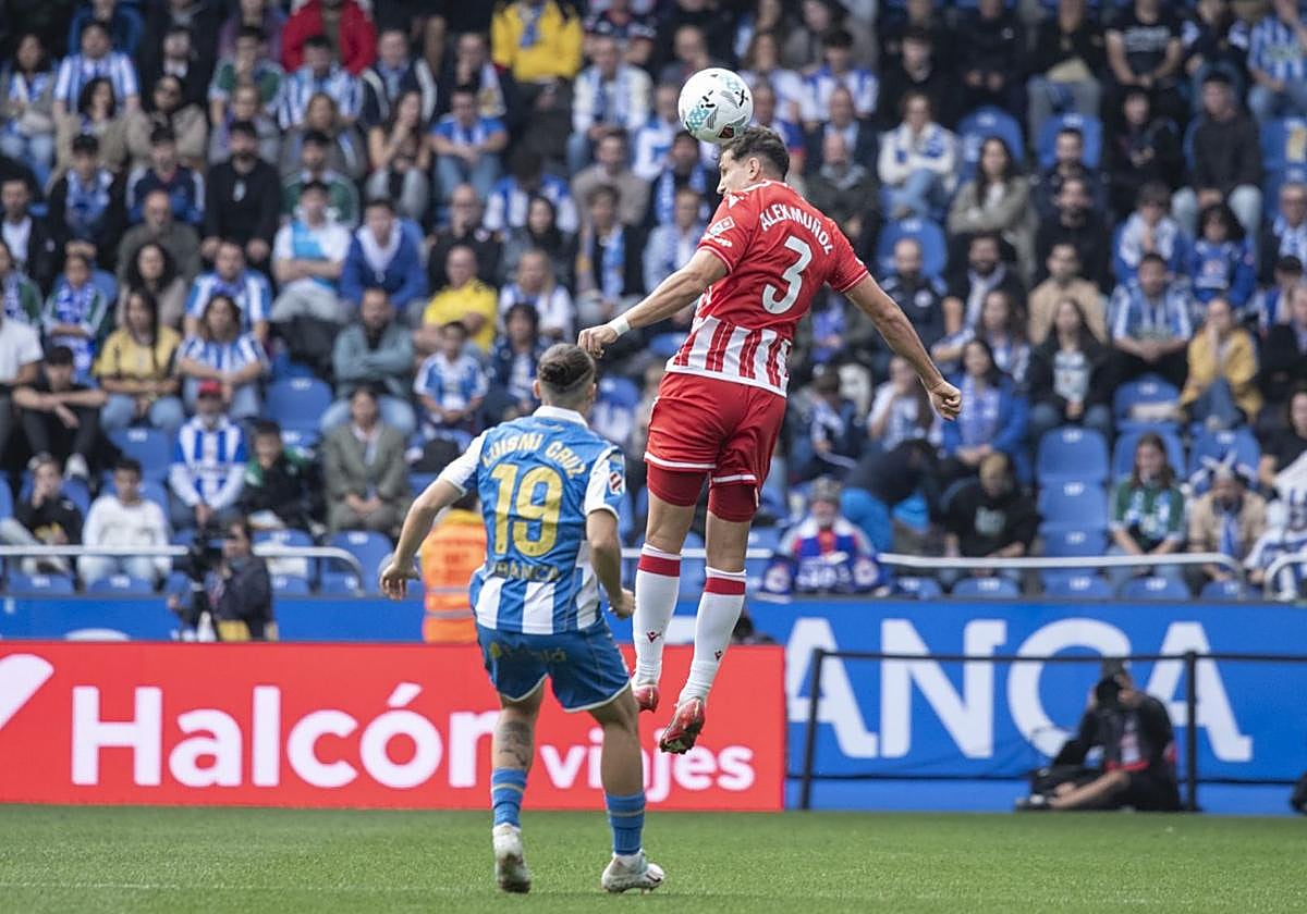 Álex Muñoz cabeceando un balón ante la mirada de Luismi Cruiz