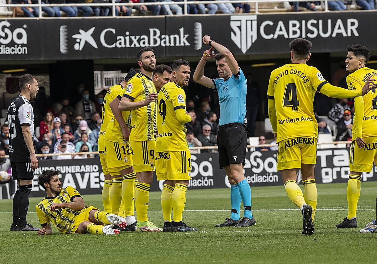 El colegiado Álvaro Moreno interactúa con los jugadores del Cartagena y del Oviedo en un partido de Segunda.