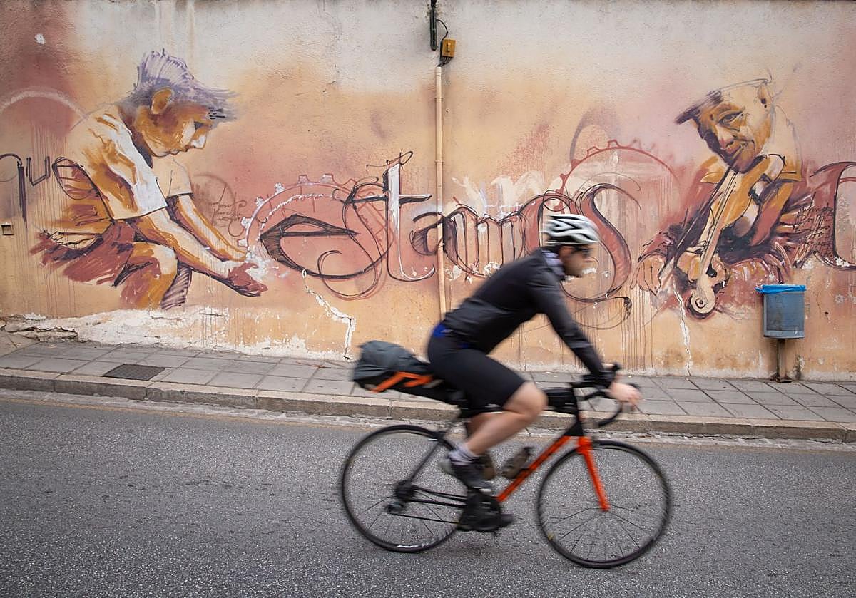 Ciclista pasa por delante de un mural en el barrio del Realejo.
