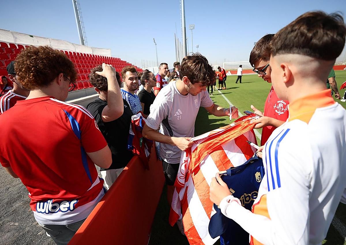 Imagen secundaria 1 - Arriba, posado de los más pequeños mezclados con el equipo. Debajo, Pablo Saénz firma una bandera a la izquierda y Samu Cortés posa para una foto a la derecha. 