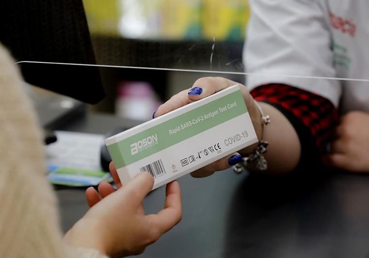 Una persona adquiere un test rápido de covid-19 en una farmacia.
