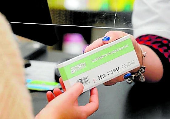 Una persona adquiere un test rápido de covid-19 en una farmacia.