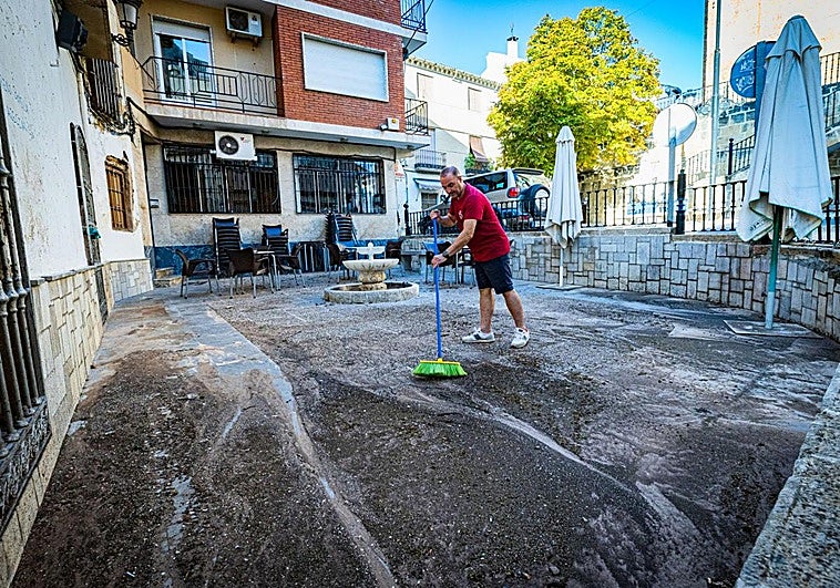 Andrés, del bar El 72, limpia la terraza de su establecimiento en la mañana del sábado, con restos de barro y piedras del aguacero.