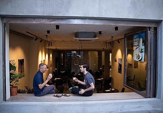 José Miguel y Luis toman un café en el gran ventanal abierto que conecta Espacio Márgenes con la vía pública.