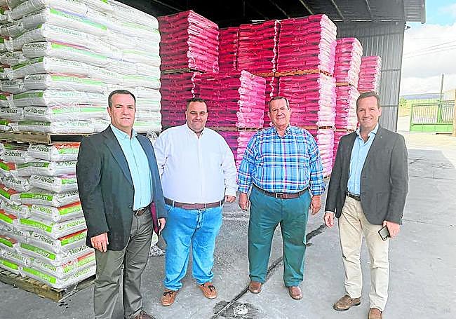 El padre y los tres hermanos junto a varios palets de producto.