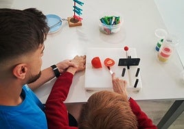 Un terapeuta ocupacional practica con una paciente neurológica cómo cortar un tomate.