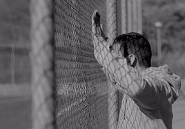 Un padre protesta, pegado a la valla, mientras su hijo juega.