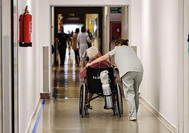 Una celadora traslada a un paciente en un hospital.