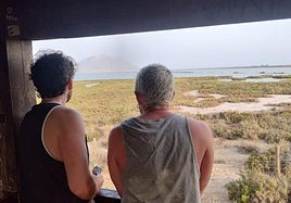 Dos turistas observan las Salinas de Cabo de Gata desde el interior de una de las casetas instaladas en el parque natural.
