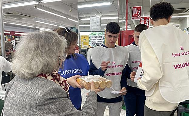 Una mujer entrega leche y galletas a los voluntarios en un supermercado Más y Más.