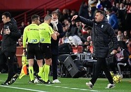 Pacheta dialoga con el árbitro principal del derbi y un linier durante el partido.