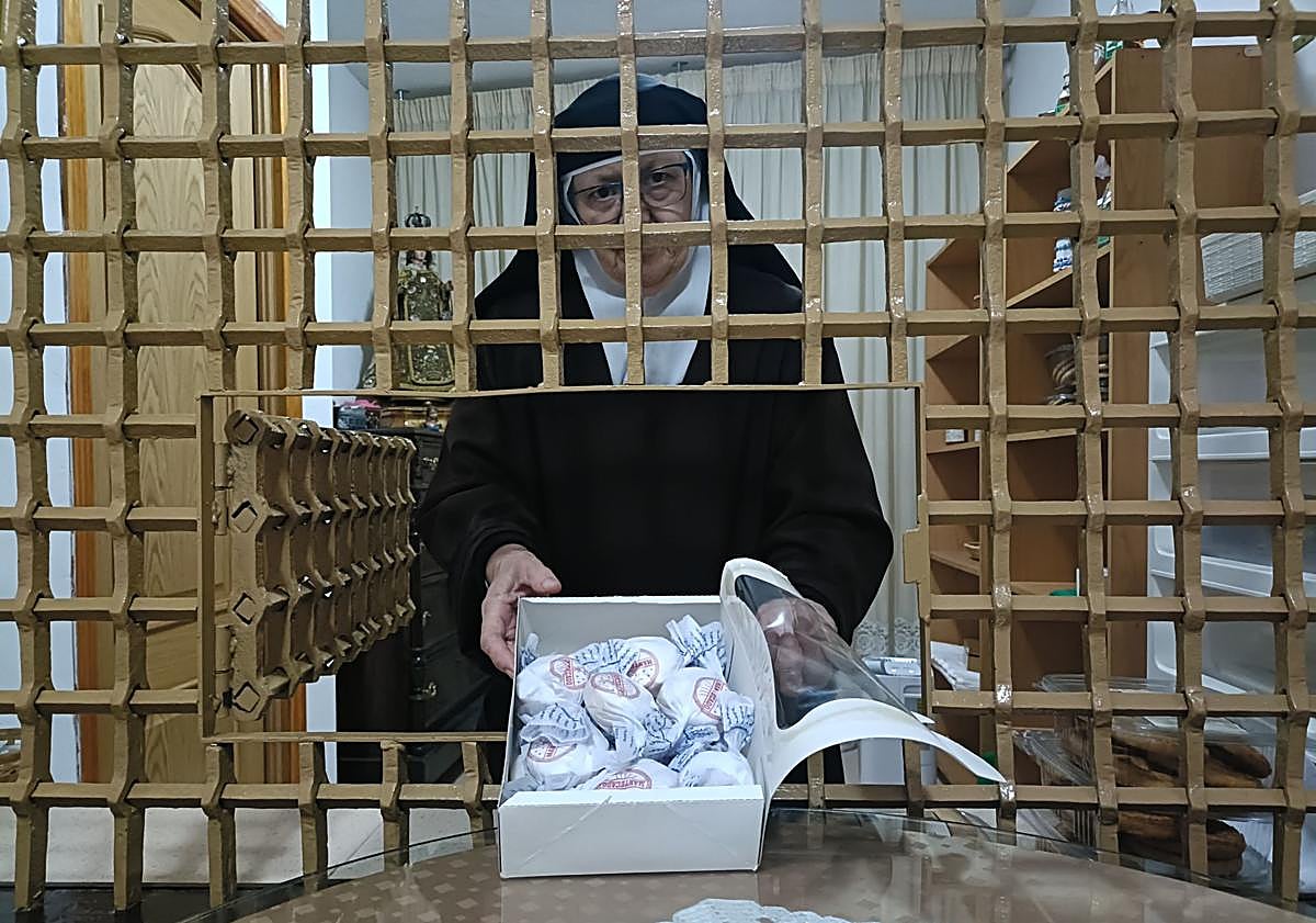 Imagen principal - La madre superiora de las carmelitas Descalzas muestra una caja con mantecados. Dos hermanas de las Comendadoras elaboran dulces.