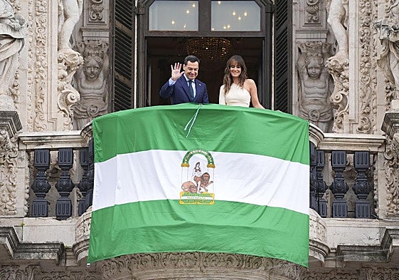 El presidente de la Junta, Juanma Moreno, despliega la bandera en el balcón de San Telmo, junto a la periodista Isabel Jiménez