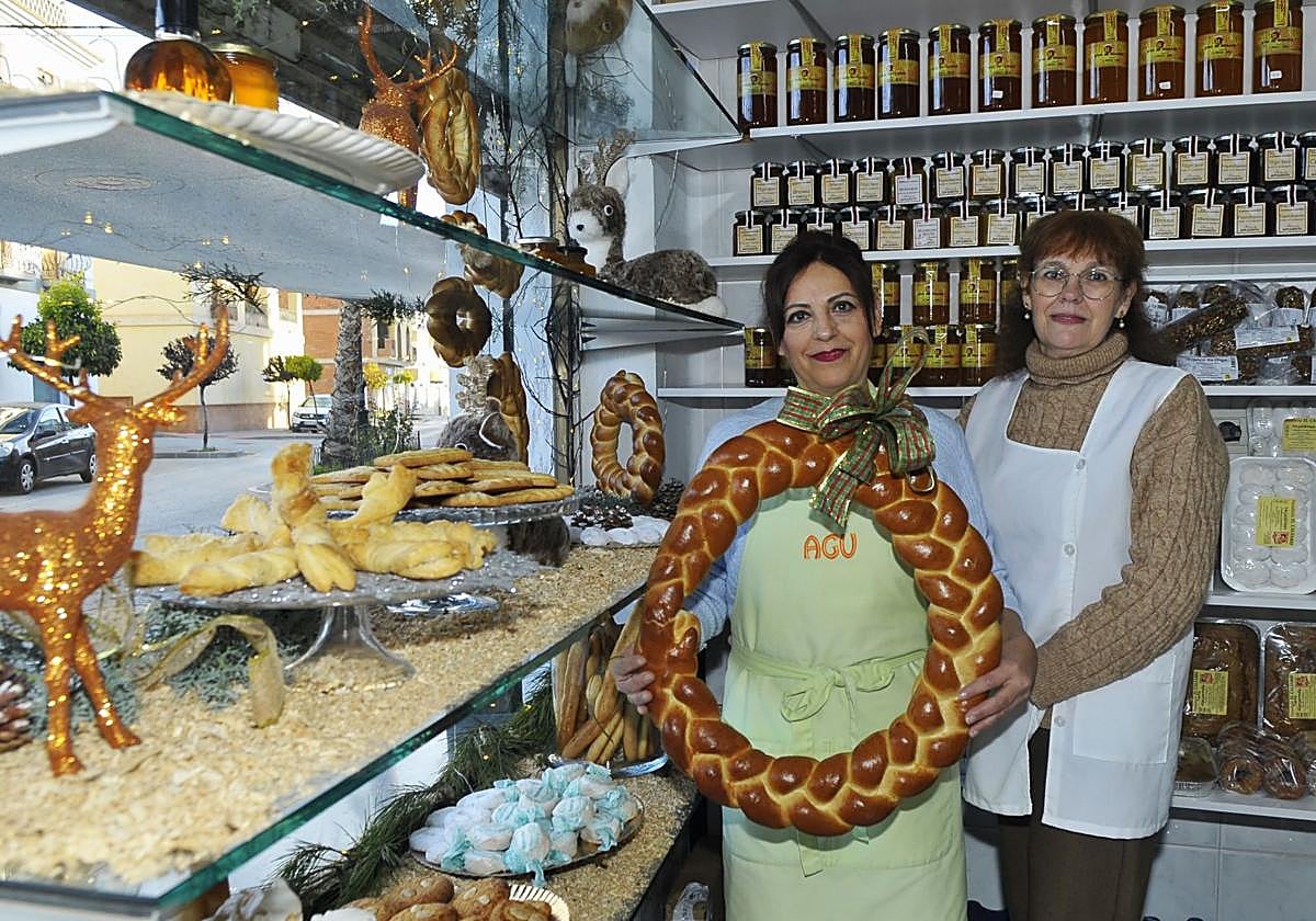 La dependienta Agustina Acuyo con una rosca de aceite navideña, junto a la propietaria, Paqui Macías, en su despacho de Cádiar.