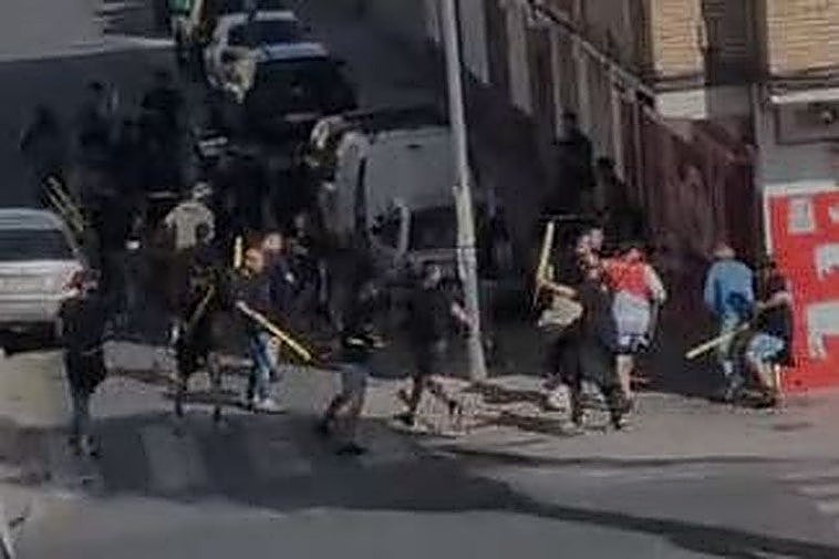 Uno de los fotogramas donde se aprecia a numerosos ultras con palos en los aledaños de Los Cármenes