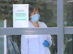 Una trabajadora del Hospital General de Almansa (Albacete) se protege con guantes y mascarilla en la puerta del servicio de urgencias del centro sanitario. / Efe