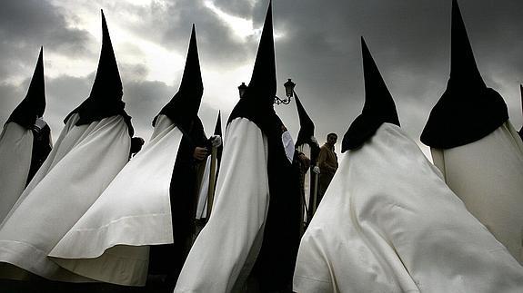 Penitentes de la hermanadad de "La Esperanza de Triana" participan en una procesión de la Semana Santa de Sevilla.