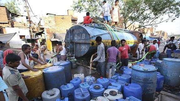 Varias personas llenan sus bombonas y contenedores de agua de un camión cisterna en Nueva Delhi.