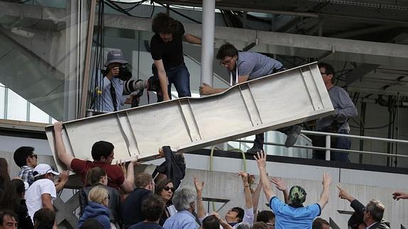 Varios aficionados sujetan la lámina metálica que se desprendió. 