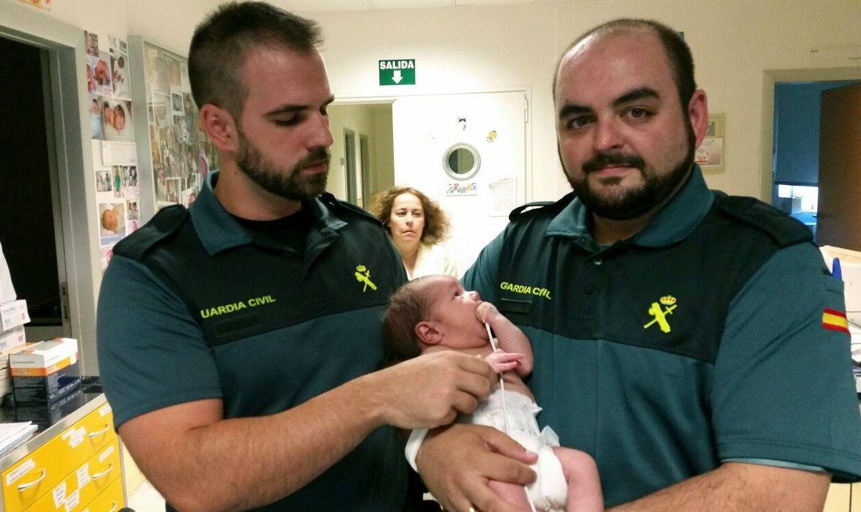 Dos agentes e la Guardia Civil junto al bebé rescatado.