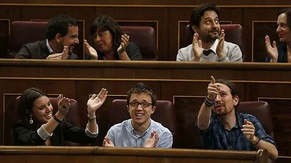Los diputados de Podemos aplauden desde su escaño tras aprobar el Pleno del Congreso la paralización del calendario de implantación de la LOMCE.