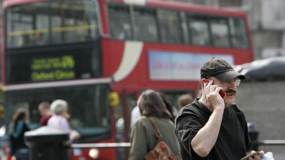 Turista habla por un teléfono móvil mientras visita Trafalgar Square, en Londres.