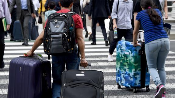 Extranjeros por las calles de Tokio con sus maletas.