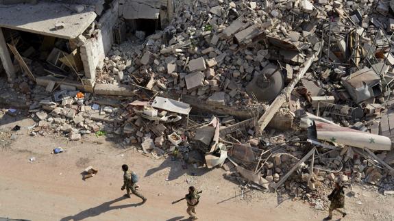 Soldados sirios caminan entre los escombros en el oeste de Alepo (Siria).