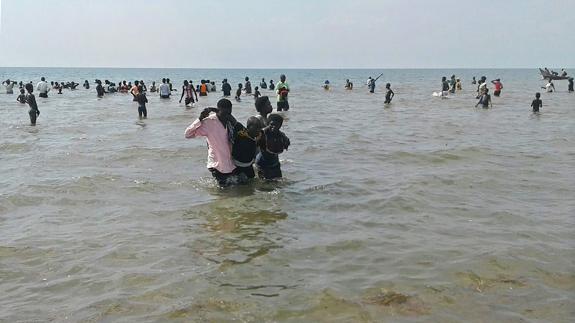 Algunos superviventes son ayudados a salir del lago Alberto, en Uganda.