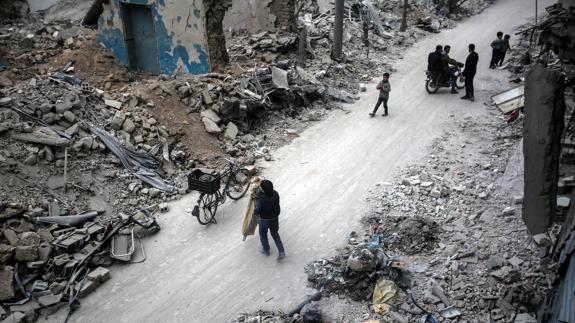 Varias personas buscan sus pertenencias entre los escombros en Douma.