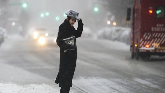 Un hombre sujeta su sombrero mientras nieva en una calle de Brooklyn, en Nueva York.