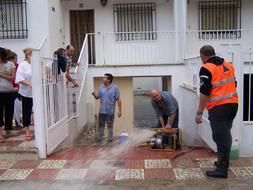 Los vecinos achican agua de los bajos de sus casas con la ayuda de Protección Civil en Pinos Puente. FOTO: A. MANSILLA