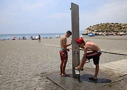 Unos jóvenes se refrescan en una ducha de Salobreña, uno de los municipios que más dificultades tiene a la hora de equipar sus playas . :: MANUEL BÉJAR