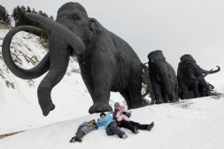 Una familia posa a los pies de los mamuts en el parque temático. / AP