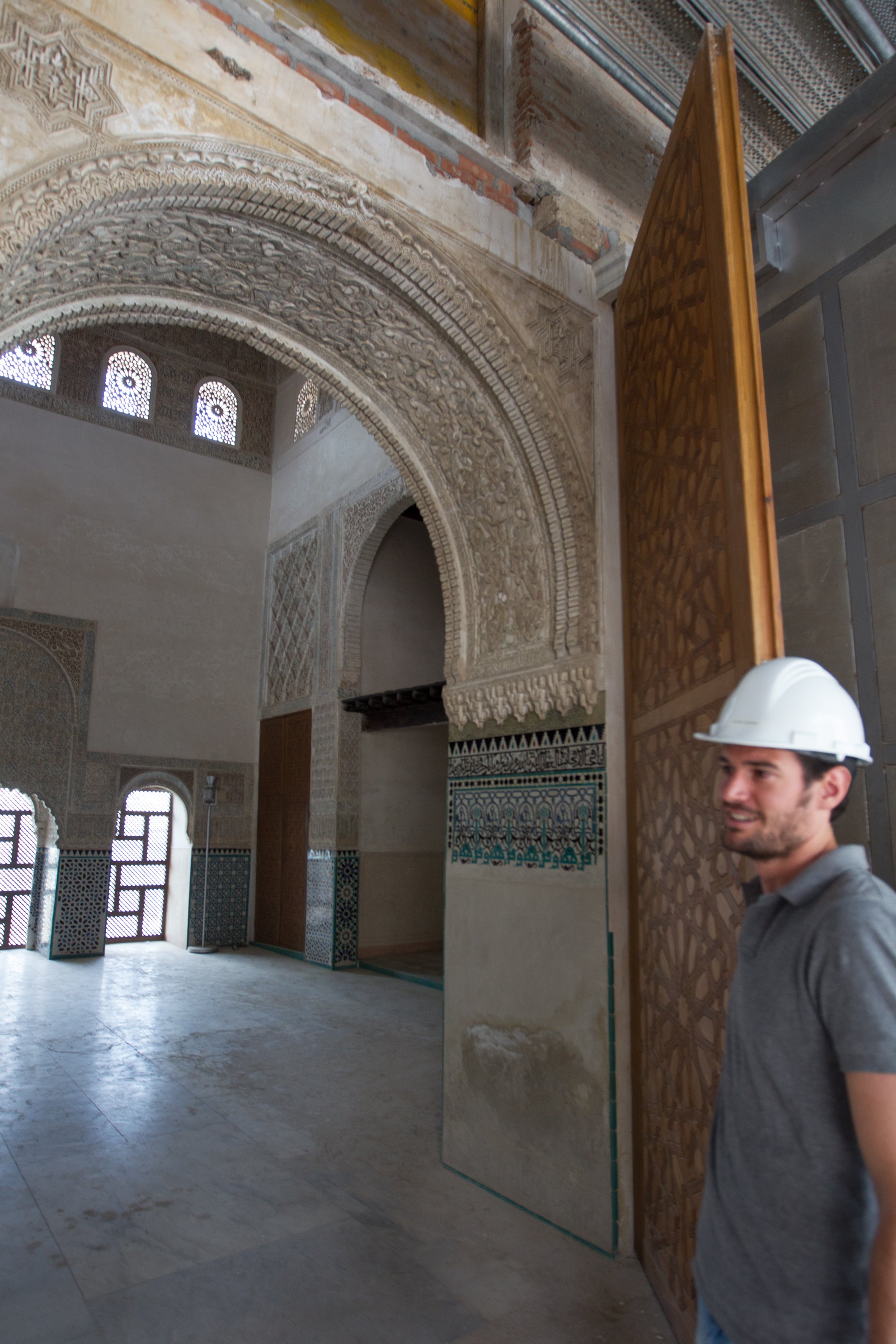 Un trabajador de las obras de rehabilitación abre la puerta tallada de la Qubba del Cuarto Real. 