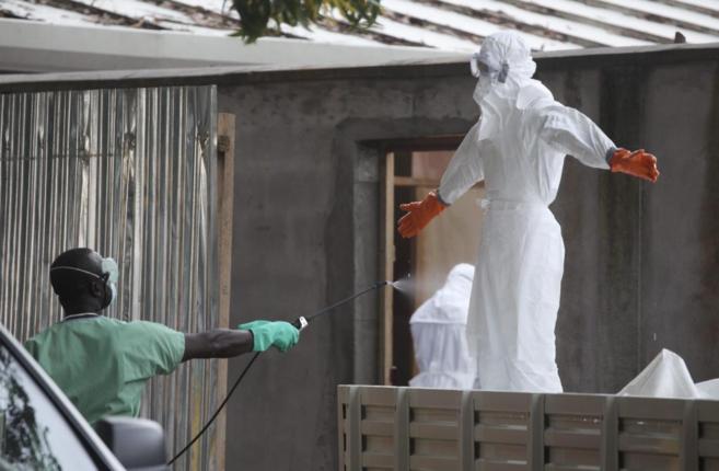 Enfermeros liberianos son fumigados con desinfectante antes de preparar los cuerpos de víctimas de ébola 