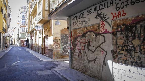 Comercios cerrados desde hace tiempo lucen grafitis sin limpiar en las calles del centro de Granada. 