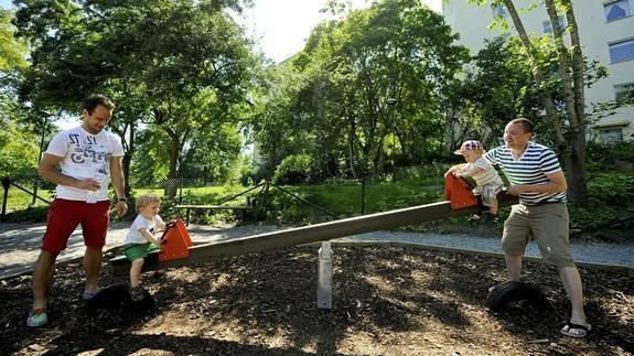 Dos padres juegas con sus hijos en un parque de Suecia 