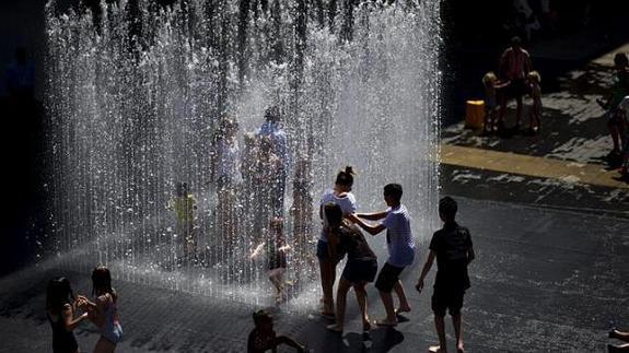 Varios niños se refrescan en una fuente en Londres. 