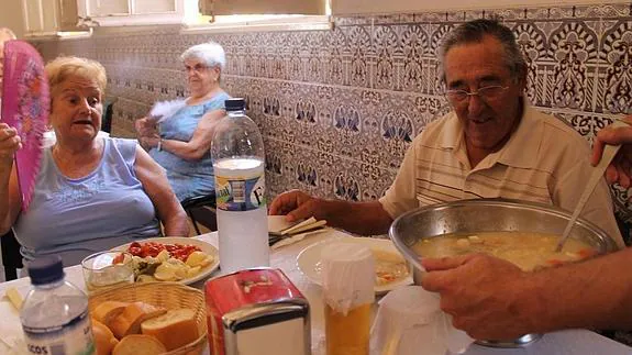 A una pareja de jubilados les sirven sopa de picadillo, lo hace un camarero hasta arriba de sudor. 