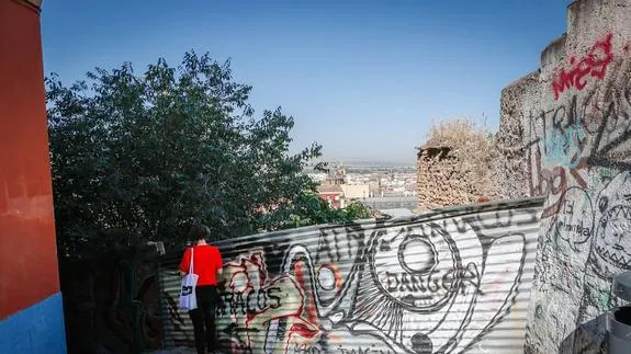 Un mural de grafiti camufla la valla que limita la acera con una zona en obras.