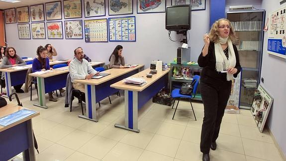 Alumnos antienden las explicaciones de una profesora en una clase en una autoescuela. 