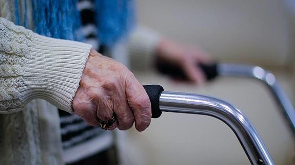 Una anciana que se vale por sí sola con ayuda anda por su apartamento privado, tutelado por la Orden de San Juan de Dios. 