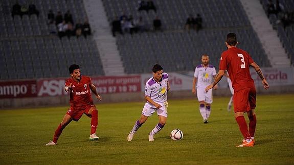 El jugador del Real Jaén defiende un balón ante el ataque de dos jugadores del Marbella. 