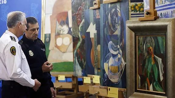 Agentes policiales contemplan las falsificaciones de los cuadros de Picasso.