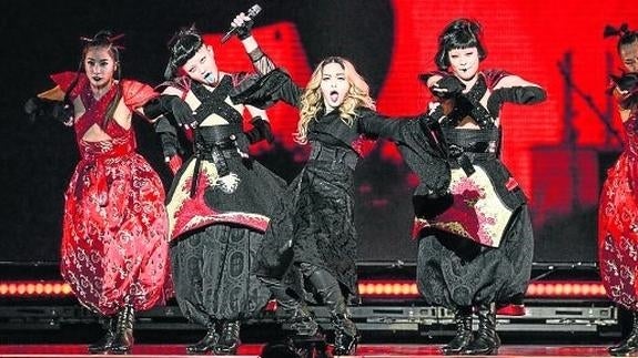 Madonna, durante el concierto en el Taipei Arena. Arriba, el momento en el que se envolvió con la bandera de Taiwán.